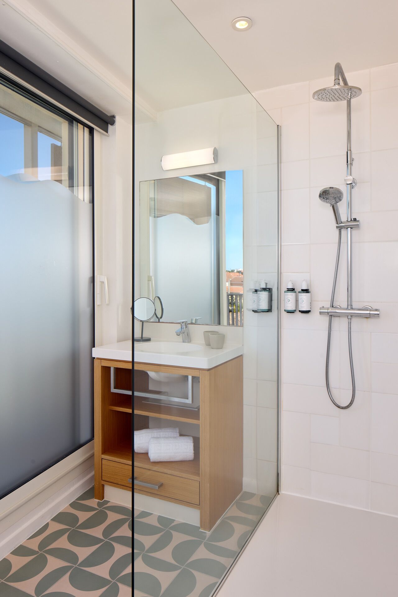 Une salle de bain moderne avec une douche à parois de verre, un meuble-lavabo en bois et un grand miroir.