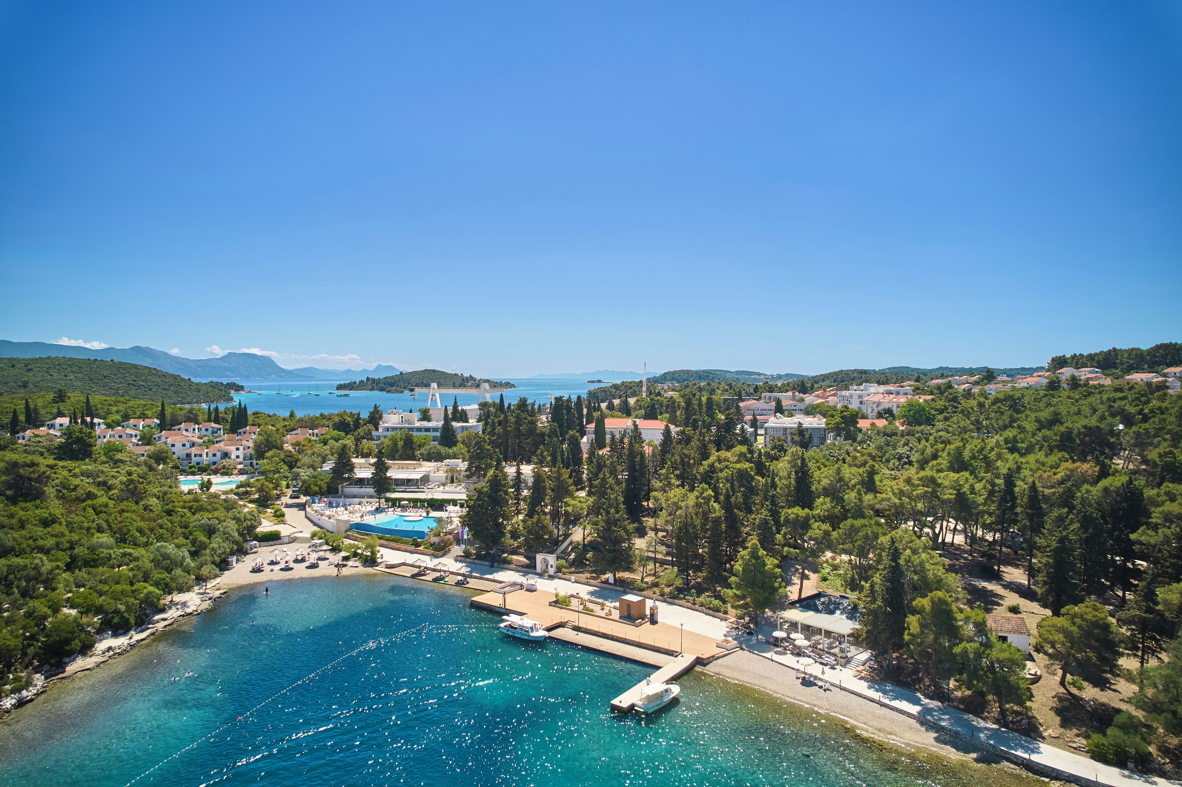 An aerial view of a coastal town with a marina, beach, and residential buildings.