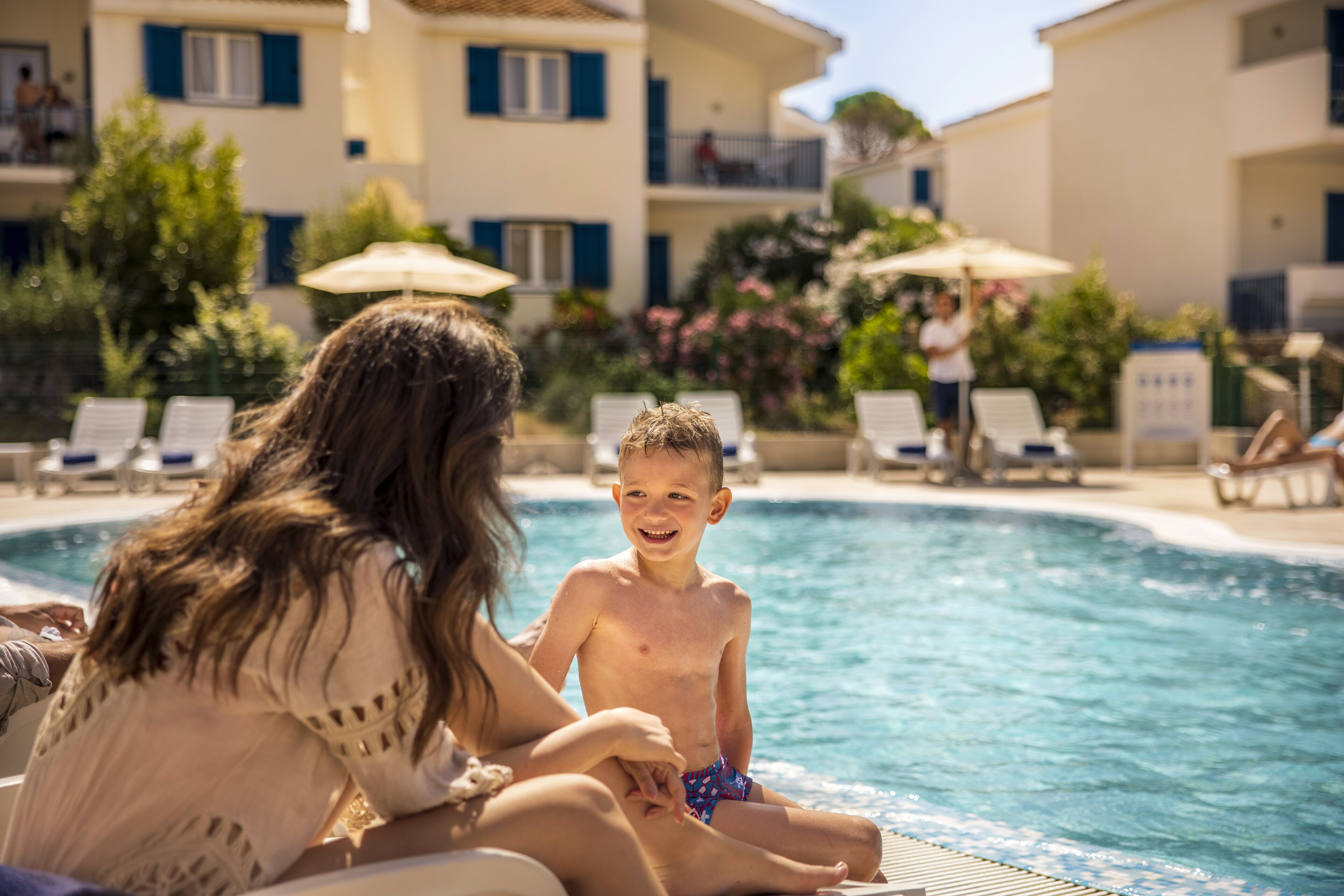 A poolside scene with a child and an adult.