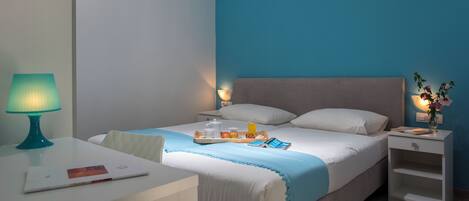 A neatly arranged hotel room with a bed, bedside tables, a desk, and a lamp.