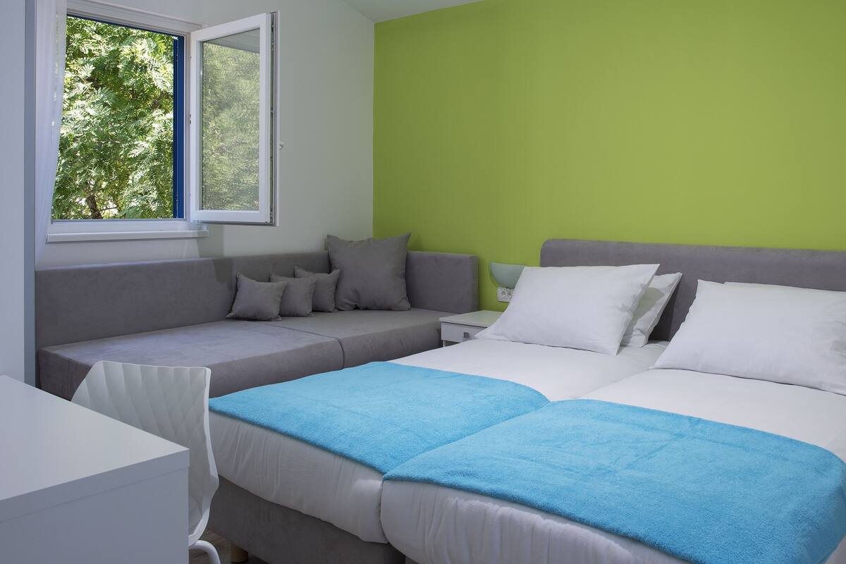A bedroom with a bed, a sofa, and a window.