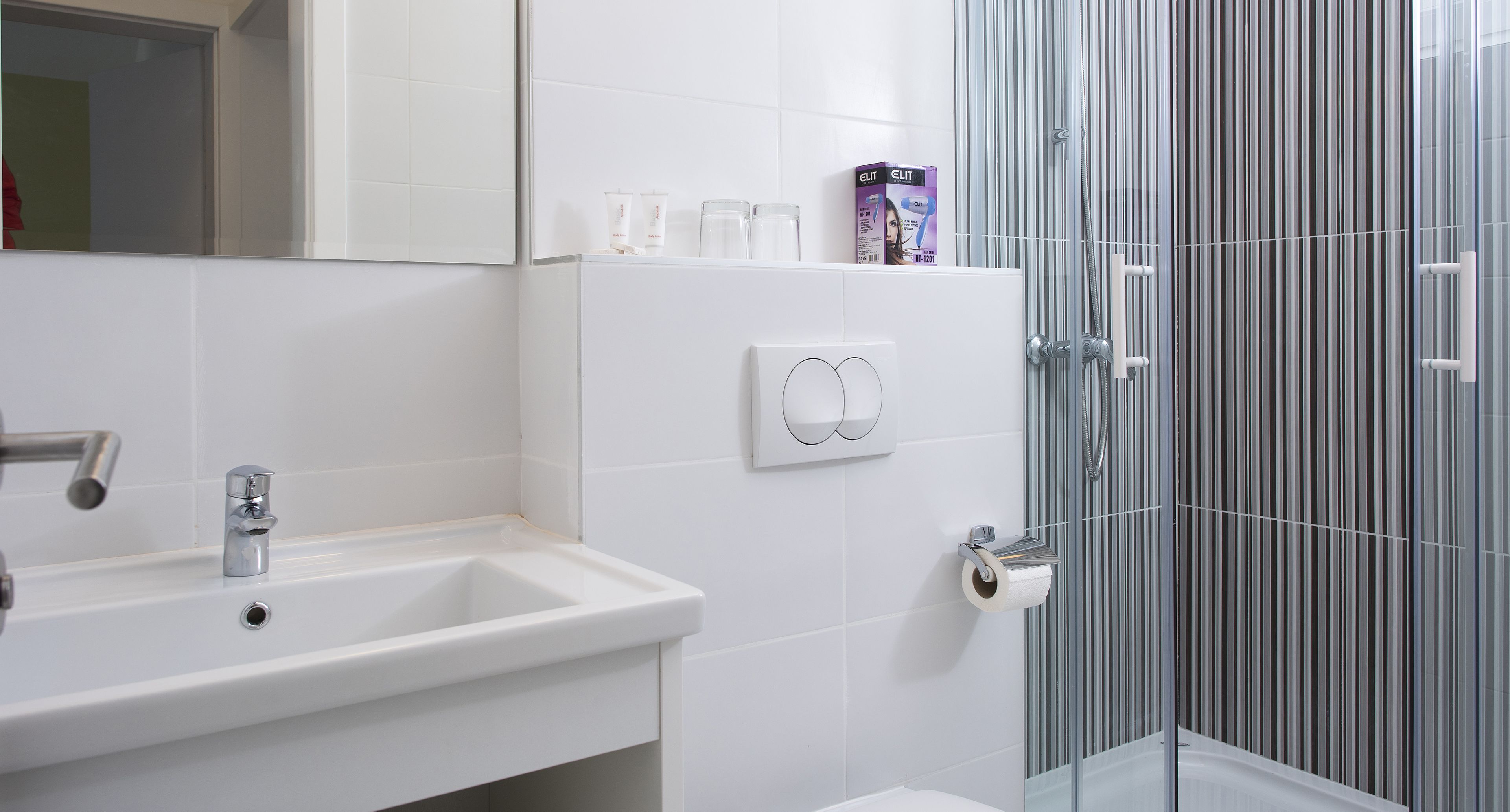 Un baño moderno con un lavabo blanco, un espejo y una cabina de ducha de vidrio.