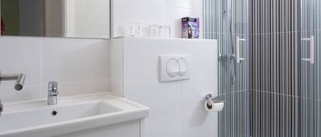A modern bathroom with a white sink, a mirror, and a glass shower enclosure.