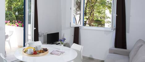 Una habitación con una mesa de comedor dispuesta para el desayuno, un sofá y una televisión.
