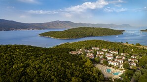 Un complejo turístico frente al mar con villas, piscina y vistas al océano y montañas.