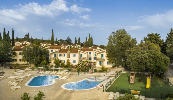 Un resort con varias piscinas, zonas de descanso y un parque infantil.