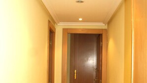 Un couloir étroit, doté d’un plancher en bois et d’une porte en bois au bout.