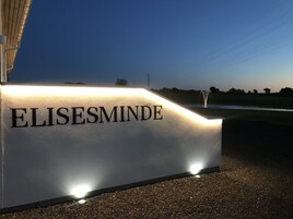 Uma placa com o nome 'ELISESMINDE' iluminado à noite.