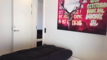Ein Schlafzimmer mit einem Bett, einer Tür und einer Wand mit einem farbenfrohen Gemälde.