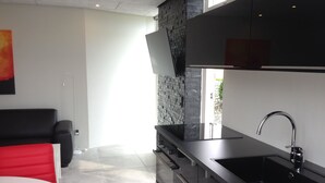 A modern kitchen with a black countertop, stainless steel sink, and a stone backsplash. - Elisesminde (Vejle)