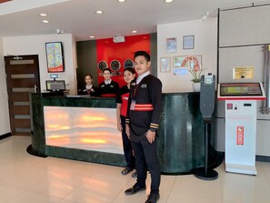 A hotel reception area with a digital display, a clock, and a waiting area sign. - Hotel Sogo Bacoor (Bacoor City)