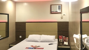 Una habitación de hotel con cama, mesita de noche y espejo.