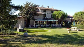 A restaurant with outdoor seating, a fountain, and a well-maintained garden.