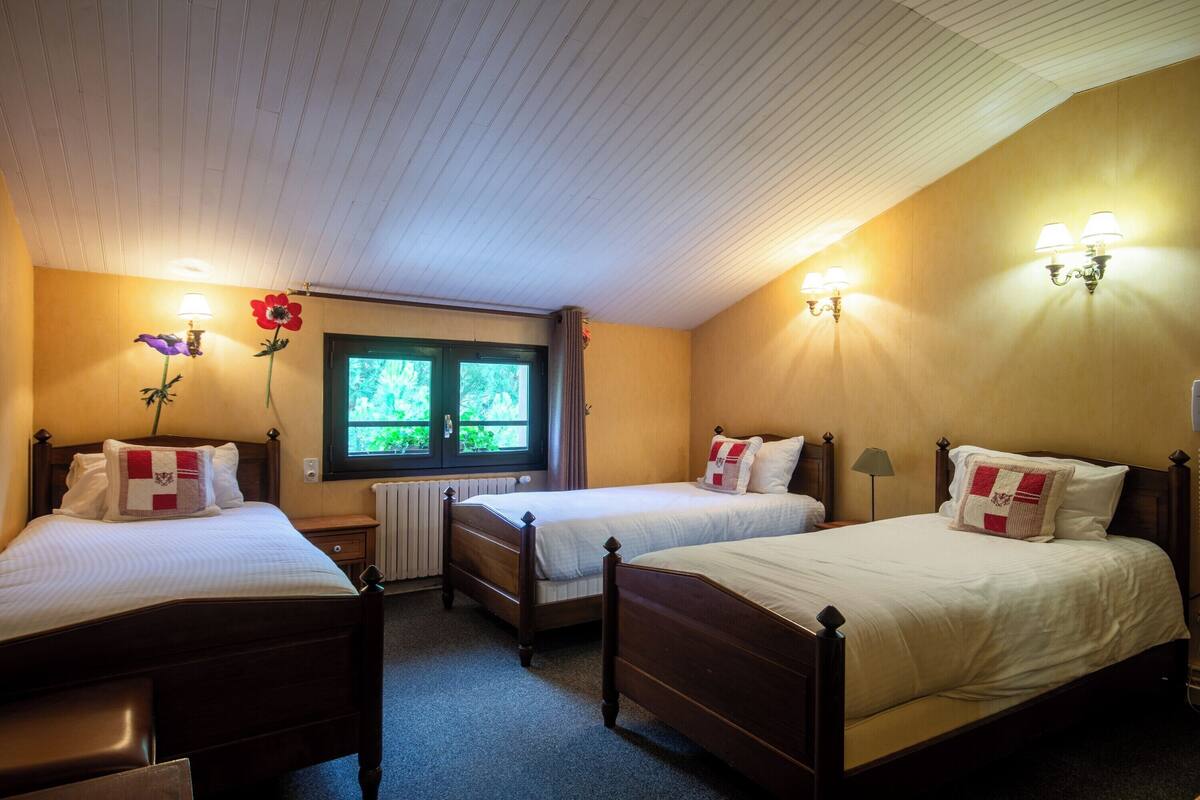Een slaapkamer met twee eenpersoonsbedden, een raam met gordijnen en wandlampen.