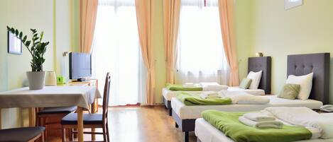 A hotel room with two beds, a desk with a computer, a chair, and a plant.