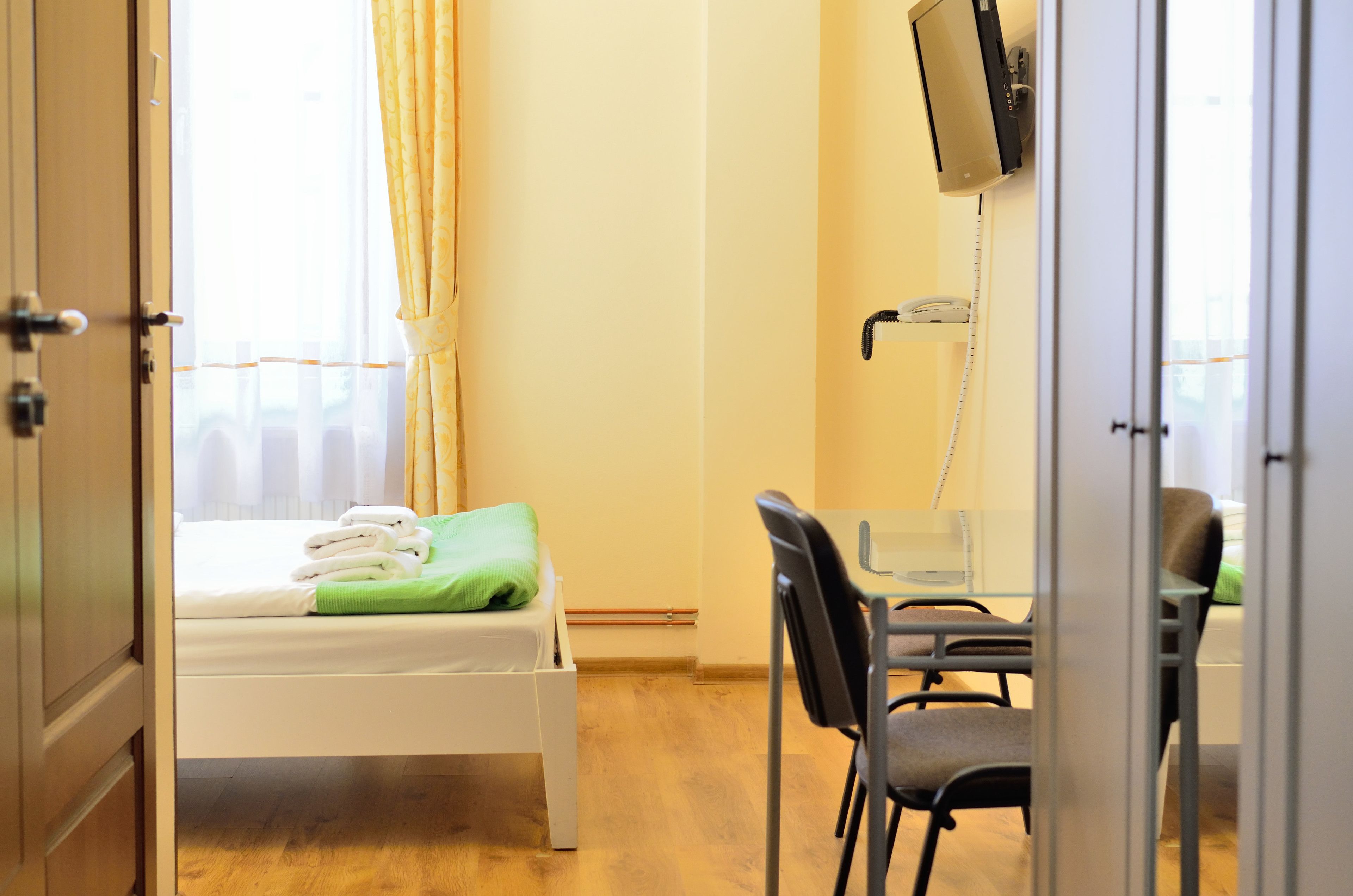 A hotel room with a bed, a desk, a chair, a television, and a telephone.