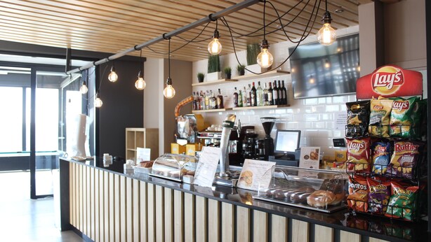 Mostrador con una máquina de café, una exhibición de bocadillos y un cartel que dice 'Bocadillos Caliente'.