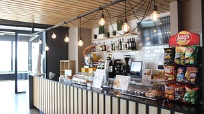 A counter with a coffee machine, a display of snacks, and a sign for 'Bocadillos Caliente'. - Residencia Universitaria Resa Erasmo (Madrid)