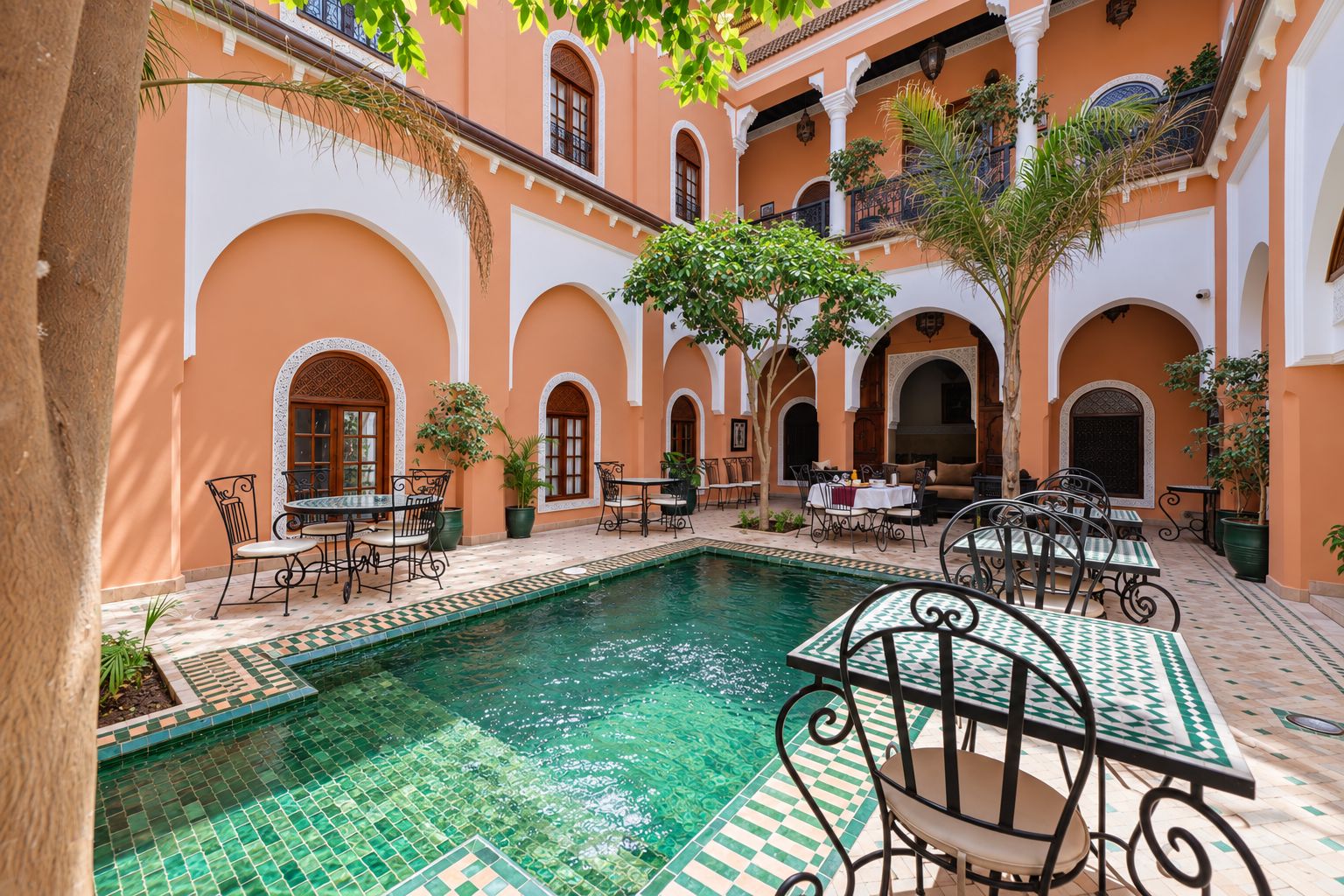 Une cour avec une piscine, des espaces de détente en plein air et des arcades.