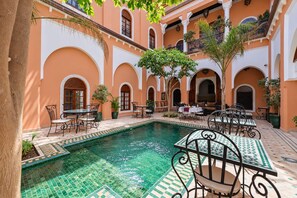 Un cortile con piscina, area salotto all'aperto e archi.