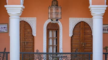 Une façade d’immeuble avec un toit en tuiles, des portes en bois et un balcon doté de balustrades en fer forgé.