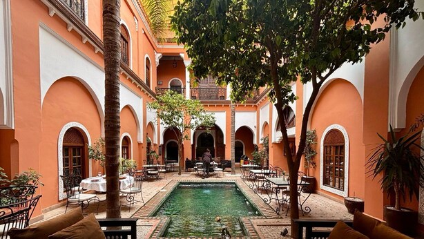Un cortile con piscina, mobili da esterno e archi.