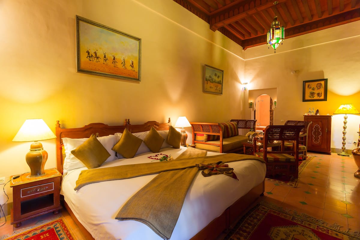 Camera d'albergo con un letto grande, una testiera in legno e una lampada decorativa.