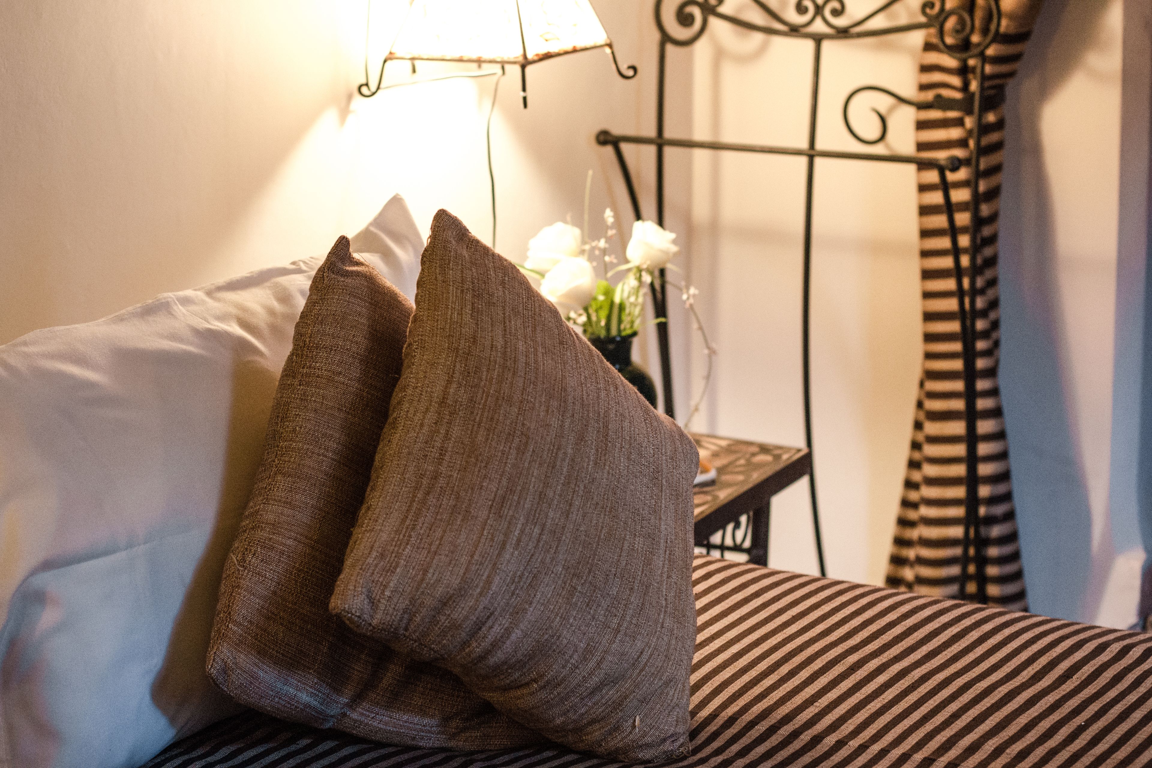A bed with striped bedding, a metal stand, and a lamp.