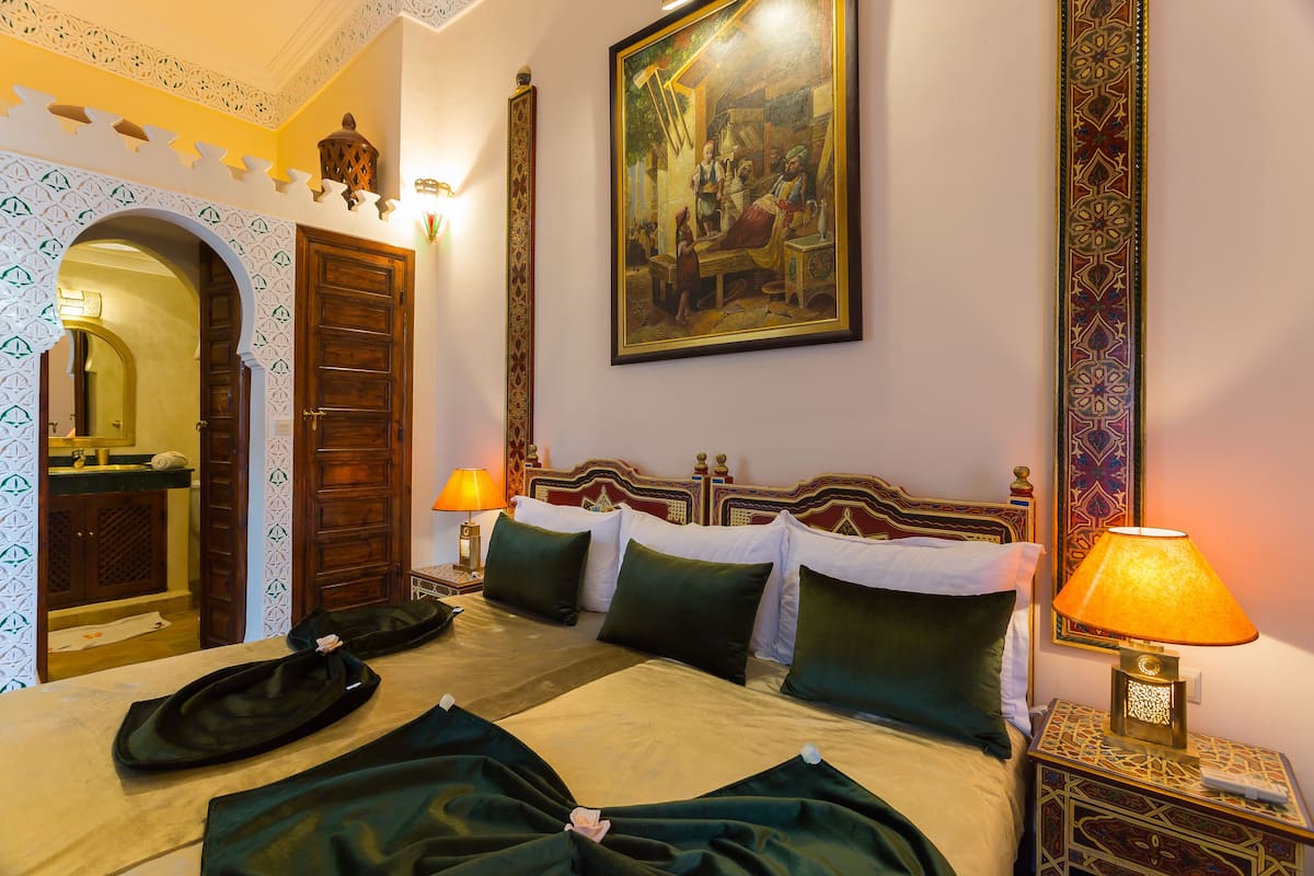 Una camera d'albergo con un letto, due comodini, una lampada e un quadro appeso al muro.