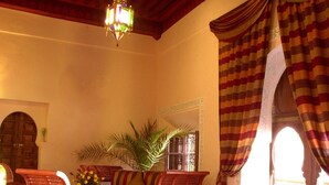 Una stanza con un letto, un soffitto in legno, un lampadario, un divano e una finestra con tende.