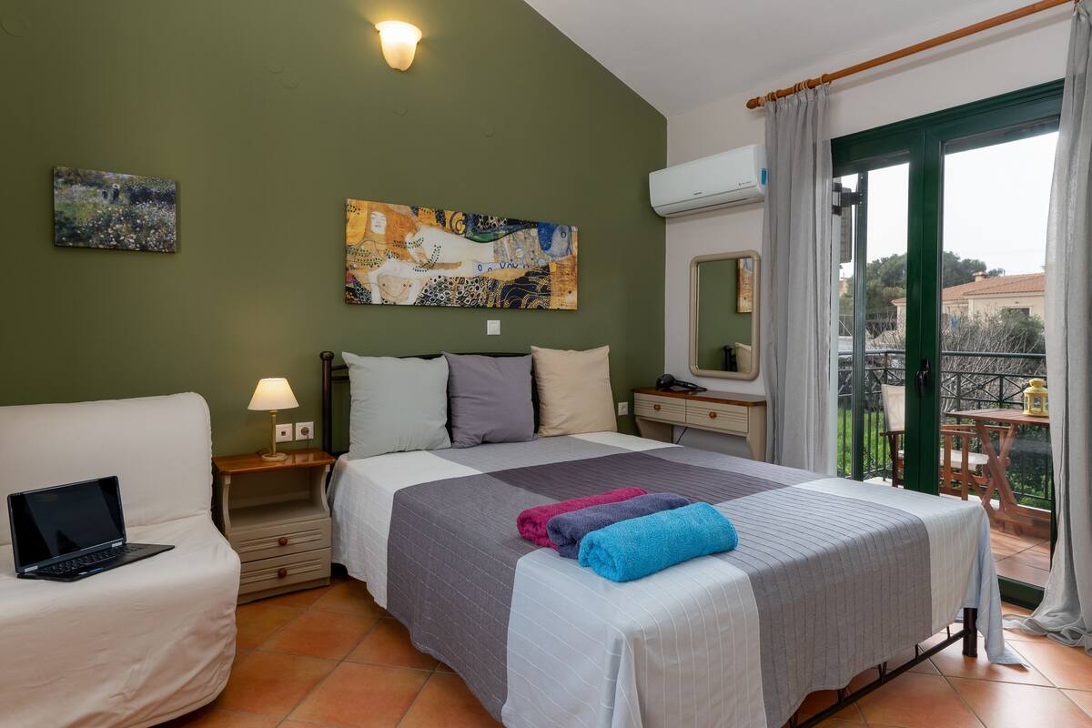 Une chambre avec un lit, un bureau, une chaise et un balcon offrant une vue.