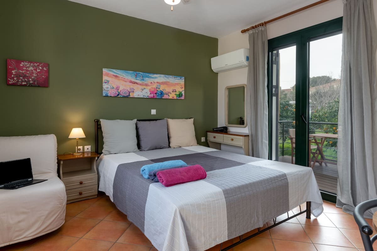 Une chambre d’hôtel avec un lit, un bureau, une chaise, un ordinateur portable, une lampe et un tableau au mur.