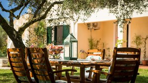 Un espace extérieur aménagé pour prendre les repas, avec une table, des chaises et une lanterne.