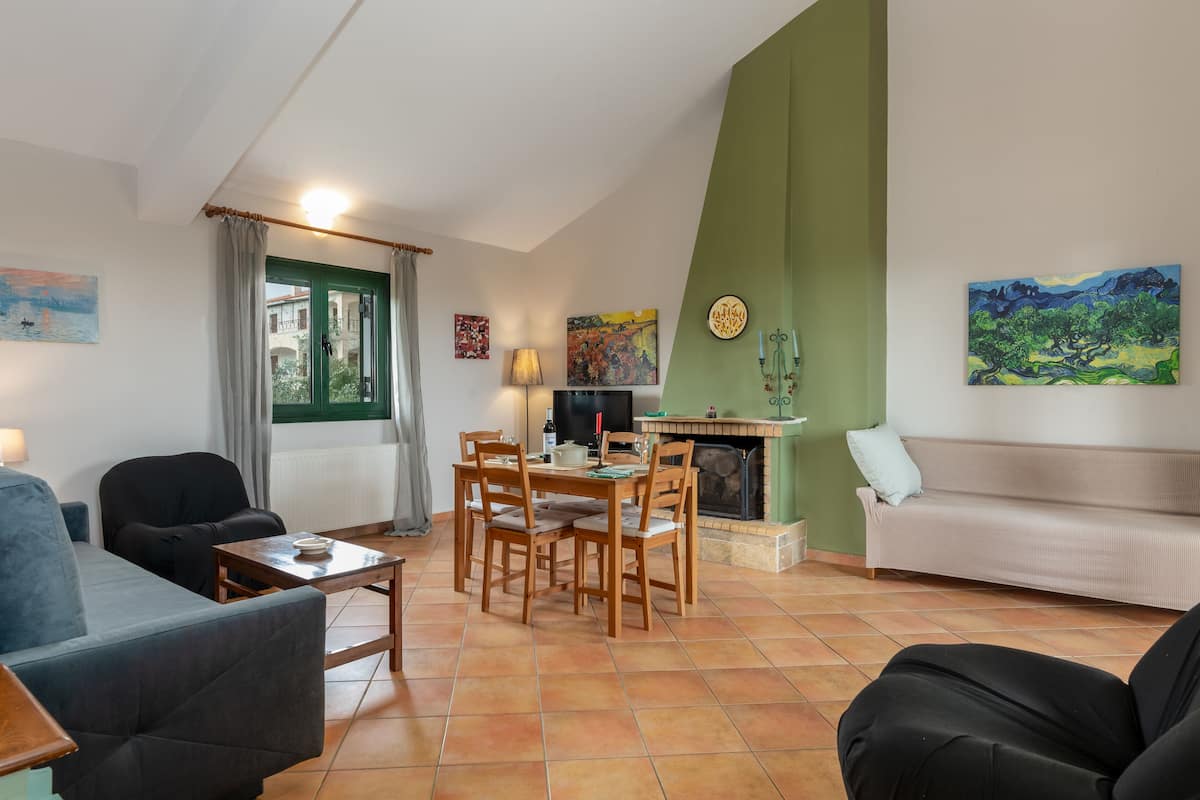 Un salon avec une cheminée, une table à manger avec des chaises, un canapé et un téléviseur.