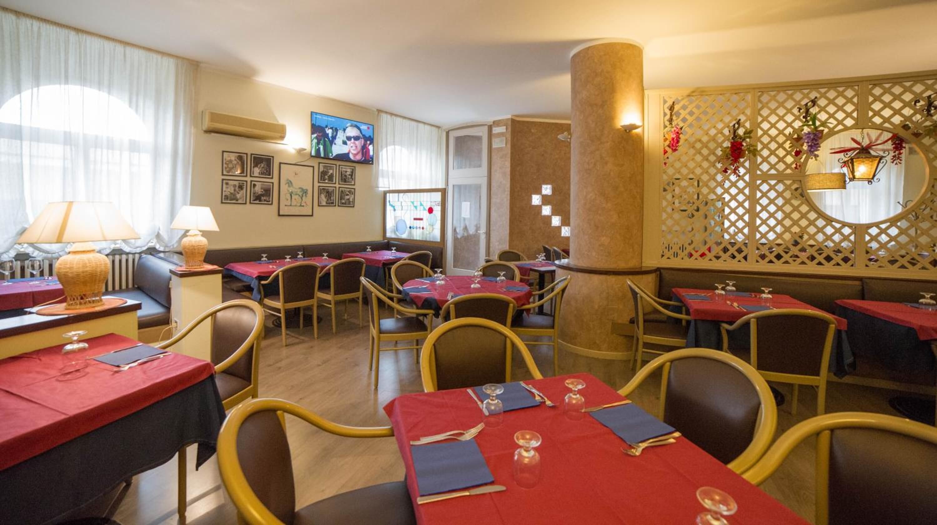 Un restaurant doté de nombreuses tables dressées pour le service, d’un coin salon avec des canapés et d’un mur décoratif orné d’un motif en treillis.