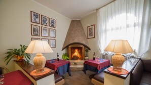 A cozy living room with a fireplace, two tables with lamps, and a couch.