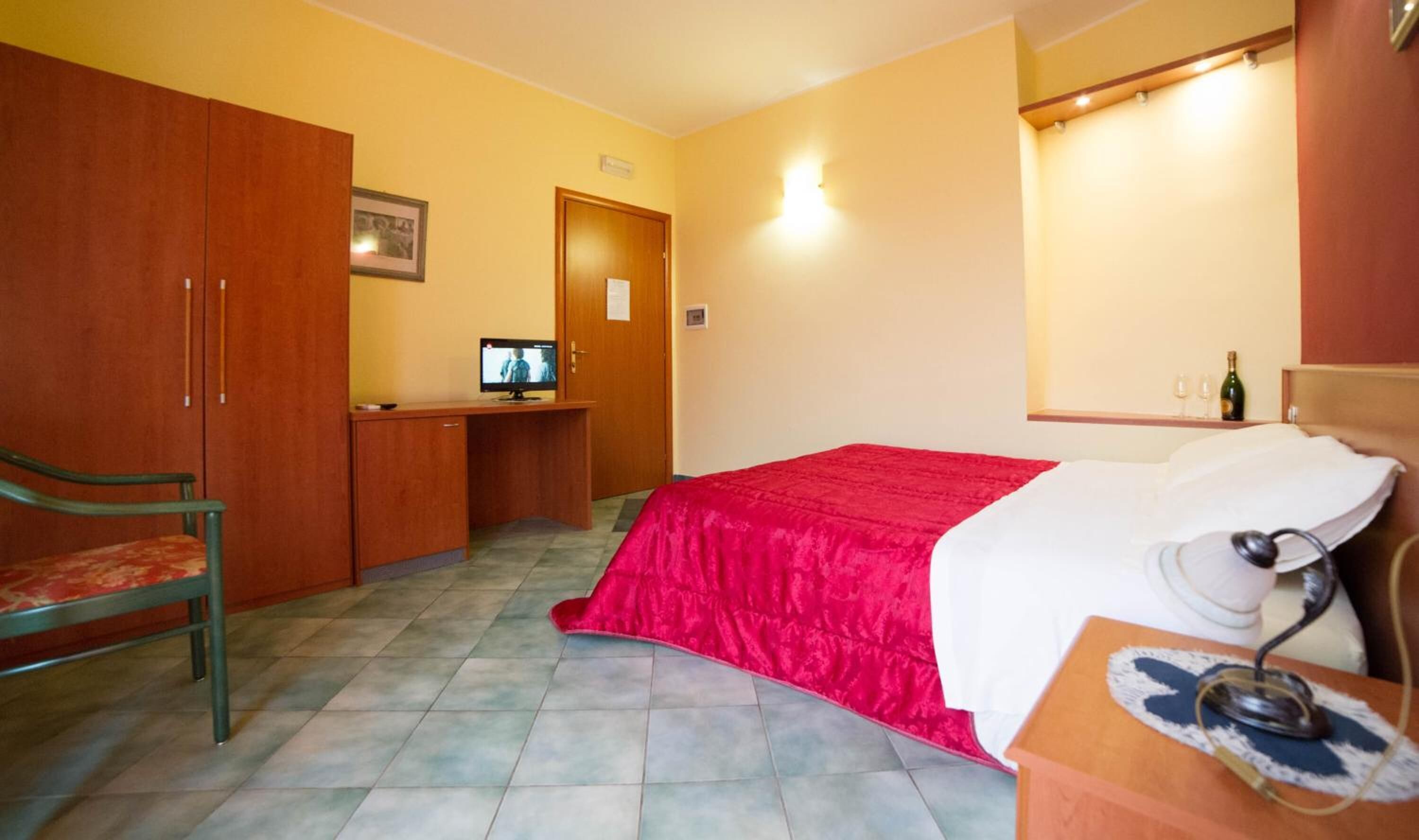 Una camera da letto con un letto, una scrivania con un computer, una sedia e un armadio.