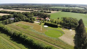 An aerial view of a rural property with a large field, a vineyard, and a house with a red roof. - Egebjerggaard Bed & Breakfast (Varde)