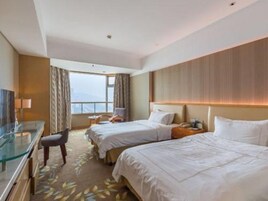 Habitación de hotel con dos camas, un escritorio y vista a la ciudad.