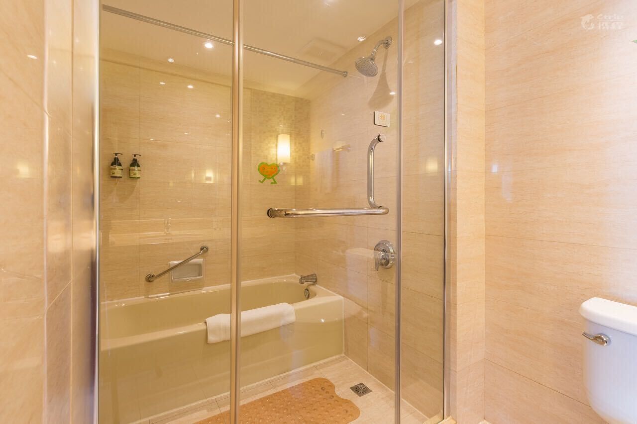 A glass-enclosed shower area with a bathtub and a toilet.