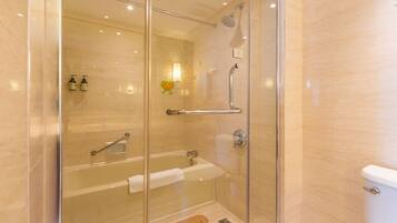 A glass-enclosed shower area with a bathtub and a toilet.