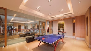 A modern indoor space with a ping pong table, exercise equipment, and a glass wall reflecting the room. - Shuguang International Hotel Nanjing (Nanjing)