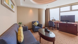 A hotel room with a sofa, armchair, coffee table, TV, and a desk with a chair. - Shuguang International Hotel Nanjing (Nanjing)