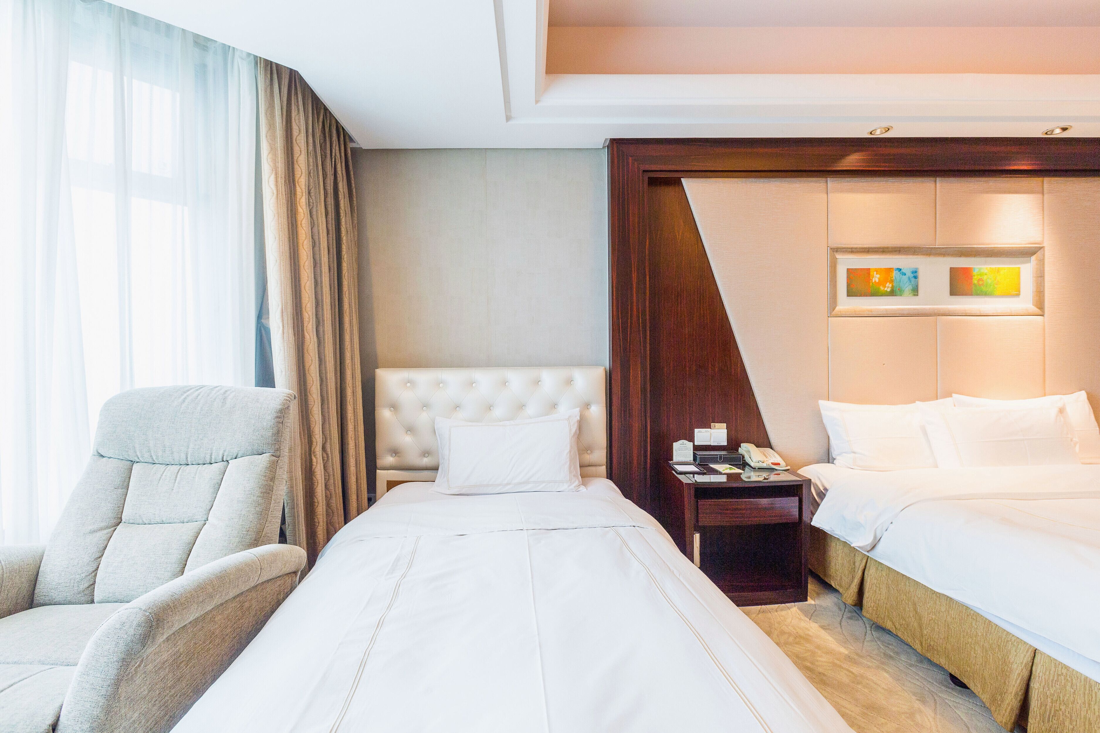 Een hotelkamer met een groot bed, een stoel, een nachtkastje en een televisie aan de muur.