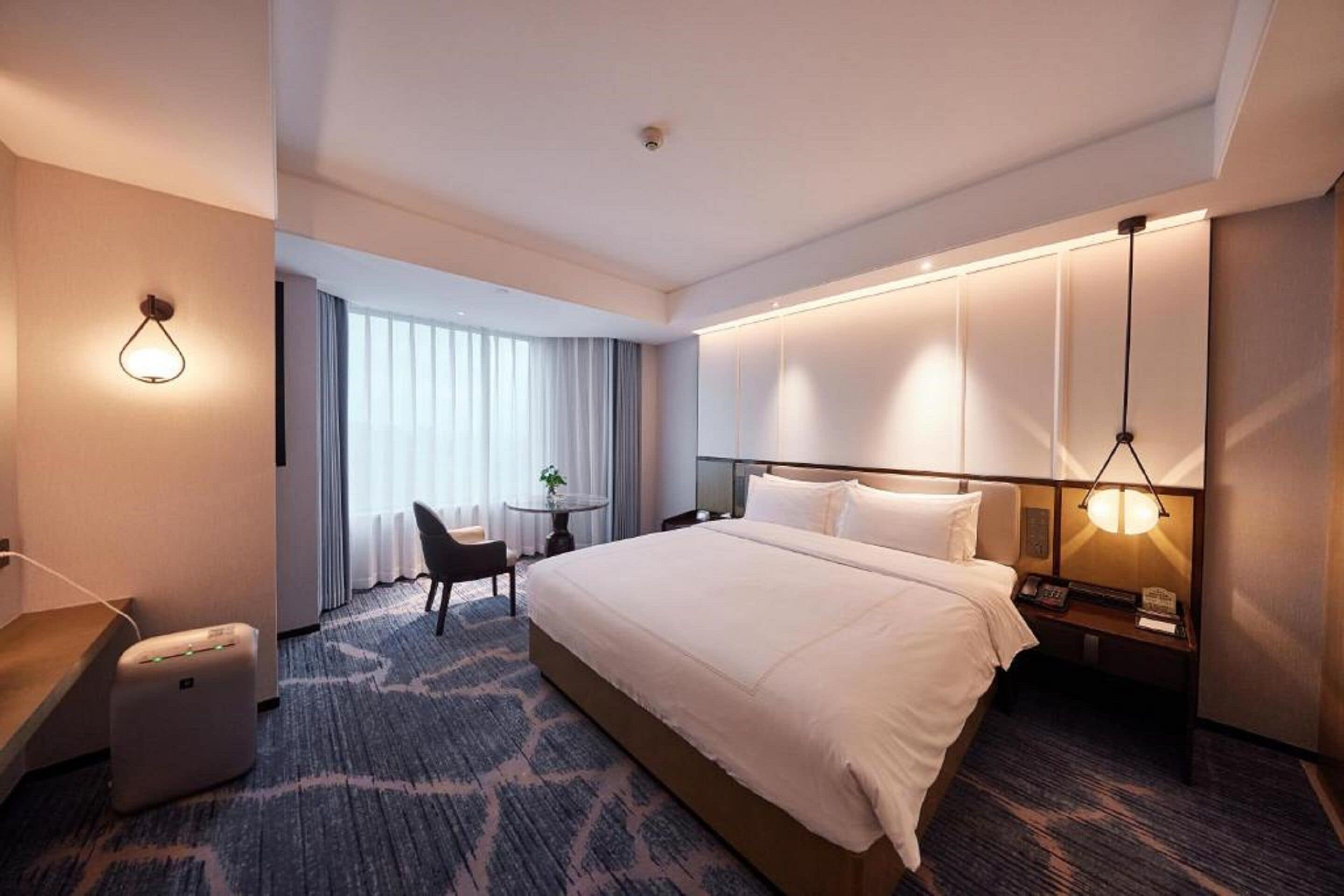 Ein Hotelzimmer mit einem großen Bett, Nachttischen, einem Schreibtisch und einem Sessel.