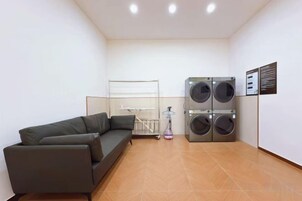 Une pièce de taille modeste, comprenant un canapé, un lave-linge et une petite fenêtre.