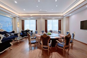 A spacious room with a round table, comfortable seating, and a large window.