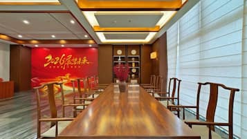 A conference room with a long wooden table, chairs, and a red banner with yellow text.