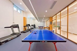 Una habitación con mesa de ping pong, equipo de ejercicio y un amplio ventanal.