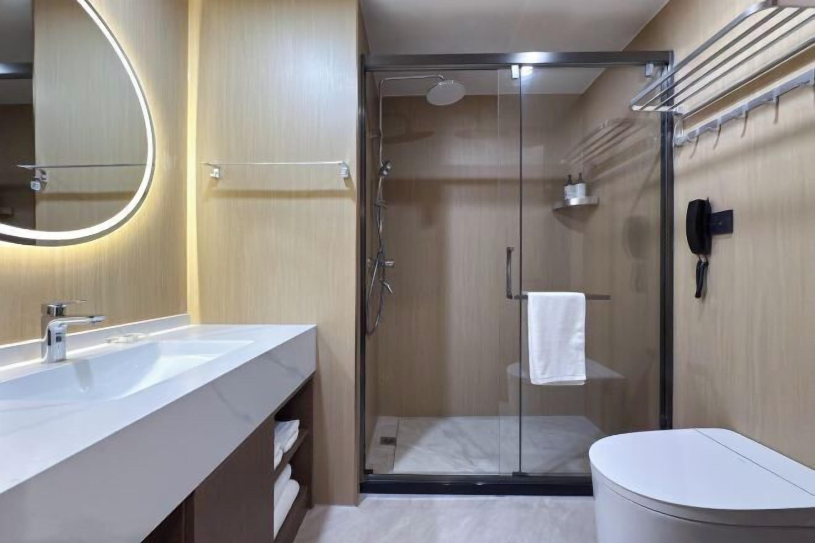 A modern bathroom with a glass-enclosed shower, a white sink, and a toilet.